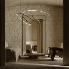 Nowoczesne lampy na poddasze skosy, wiszące nad kamiennym wnętrzem z sofą i fotelami.