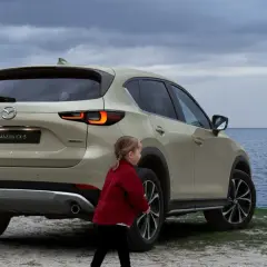 Rodzina przy nowej Mazdzie CX-5 na tle morza. Dzieci i matka spacerują brzegiem.