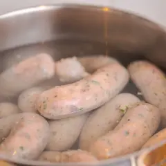 Kiełbasy w garnku z wodą, gotowe do wędzenia. Zastanawiasz się, jak długo wędzić kiełbasę bez parzenia?