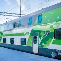 Ein moderner Doppelstockzug der VR in Finnland, verziert mit Eulen und Sternen, fährt durch eine verschneite Landschaft.