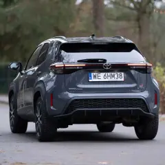 Szary Toyota Yaris Cross hybrydowy z tyłu na drodze.