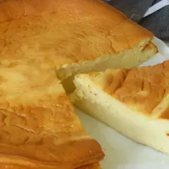 Tarta de queso Philadelphia dorada y esponjosa, con una porción cortada que revela su interior cremoso.