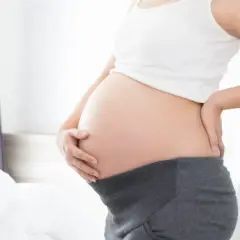 Brzuszek w 21 tygodniu ciąży. Delikatne dotknięcie dłonią, oczekiwanie na maluszka.