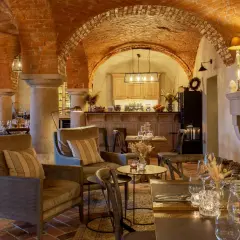 Wnętrze restauracji z ceglanymi łukami, kominkiem i stołami.