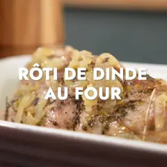Un rôti de dinde au four, savamment assaisonné d'herbes et d'oignons, cuit à la perfection dans un plat en céramique.