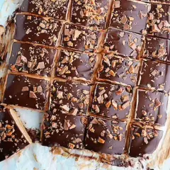 Biskvier i långpanna från Lindas bakskola, täckta med choklad och strössel. En gyllene kniv ligger bredvid.