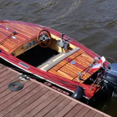 Piękna drewniana łódka z silnikiem Yamaha, zacumowana przy pomoście. Idealna do rejsów, jak zbudować taką łódkę?