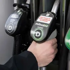 Hand håller dieselslang, funderar på dieseltillsats bra eller dåligt. Bredvid finns bensinslang.