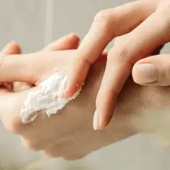 Delikatny peeling do rąk rozprowadzany palcami, z widocznym zadbanym paznokciem.