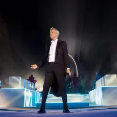 Claudio Baglioni in smoking, sul palco con orchestra e coristi, un momento iconico della sua biografia artistica.
