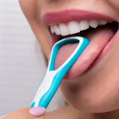 Una persona usa un puliscilingua blu e bianco per pulire la sua lingua. Un gesto che ricorda una lava lingua.