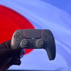 Dłoń trzyma biały kontroler DualSense. Czy gry z PS4 działają na PS5? Tak, większość z nich!
