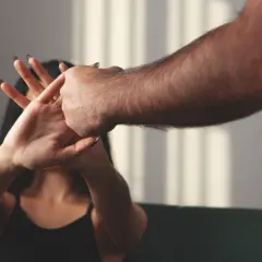 Dłoń kobiety zasłaniająca twarz przed męską ręką.