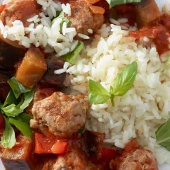 Herzhafte Salsiccia-Zubereitung in der Pfanne mit Auberginen, Paprika und Reis, garniert mit frischem Basilikum.