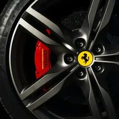 Felga z logo Ferrari, czerwony zacisk hamulcowy Brembo i opona Pirelli. Marka samochodu na i.