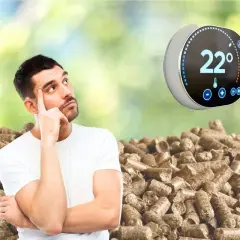 Un homme réfléchit devant un tas de granulés de bois, un thermostat connecté pour poêle à granulé affiche 22°.