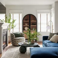 A round coffee table decor features a vase with greenery and a beaded strand, adding a natural touch to the living room.