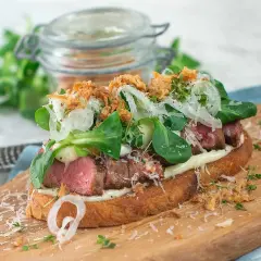 En läcker steak sandwich med mört kött, krispig sallad, lök och parmesan på rostat bröd.