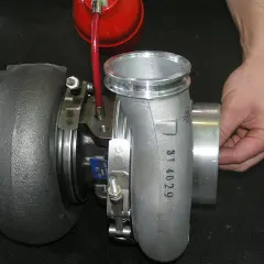 Ustawienie sztangi turbiny domowym sposobem. Dłoń trzyma element turbosprężarki, obok czerwony zbiorniczek.