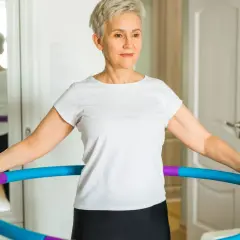 Kobieta ćwiczy z hula hop, zastanawiając się, ile trzeba kręcić hula hop żeby schudnąć.