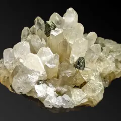 Ein Cluster aus klaren, facettierten Quarz-Kristallen mit dunklen Einschlüssen. Was ist Quarz? Ein faszinierendes Mineral!