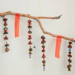 Ein schönes Herbst-Mobile zum Basteln mit Kindern: Kastanien, Beeren und bunte Perlen hängen an einem Ast.