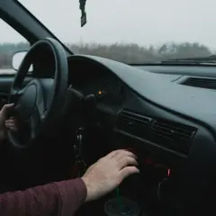 Ręka kierowcy manipuluje radiem samochodowym, szukając wskazówek, jak wyciągnąć radio samochodowe.