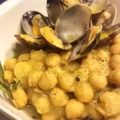 Un piatto invitante di ceci e vongole, condito con erbe aromatiche e pepe nero.