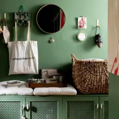 Charming apartment entryway ideas: green cabinet with cushions, tote bag, mirror, and woven basket.