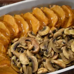 Pyszny schab z pieczarkami w sosie, podany w naczyniu żaroodpornym. Aromatyczne pieczarki idealnie komponują się z soczystym mięsem.