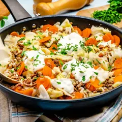 Herzhaftes spitzkohl mit hackfleisch in der Pfanne, garniert mit Klecksen saurer Sahne und Petersilie. Ein deftiges Gericht!