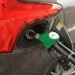 Tankowanie samochodu benzyną 95 Pb. Wlew paliwa i zielony pistolet dystrybutora.