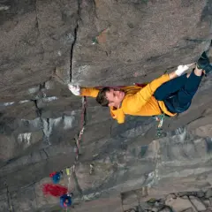 Ein Kletterer meistert eine anspruchsvolle **offwidth climbing** Route, seine Hände greifen fest in den Fels.