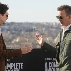 Timothée Chalamet och Edward Norton gestikulerar framför en bakgrund med texten "A Complete Unknown", en av filmerna med Timothée Chalamet.