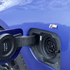Niebieskie BMW 330e z otwartą klapką gniazda ładowania. Widoczny symbol M.