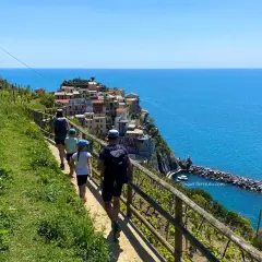 Familj på en vacker cinque terre vandring längs kusten med färgglada hus och blått hav.