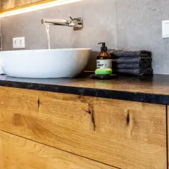 Modernes Badezimmer mit Waschtischunterschrank aus massivem Holz. Die Schubladenfronten zeigen die natürliche Maserung des Holzes, eine tolle Idee für Ihr Bad.
