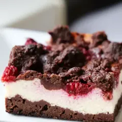 Pyszny sernikobrownie z malinami, z czekoladową kruszonką i kremowym serkiem. Idealny deser dla każdego łasucha.
