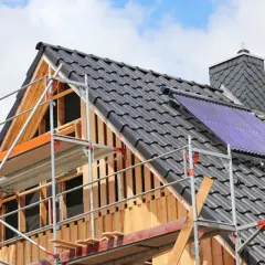 Gerüst am Dach eines Hauses, das saniert wird. Solarkollektoren sind installiert.