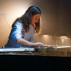 Artystka tworzy muzykę, jakby grała piosenkę z filmu Absolwent, z pasją naciskając klawisze syntezatora.