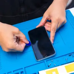 Ręce rozbierają telefon, by dowiedzieć się, jak włączyć nawigację w telefonie. Obok leży śrubokręt.