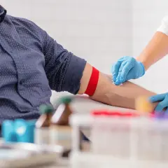 Pielęgniarka w niebieskich rękawiczkach dezynfekuje ramię pacjenta przed pobraniem krwi. Wyniki badań, w tym rdw-sd, będą gotowe wkrótce.