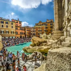 Fontana di Trevi, un vero gioiello tra gli imperdibili di Roma, affollata di turisti che ammirano la sua maestosità sotto un cielo azzurro.