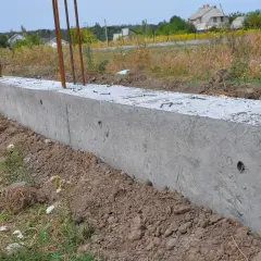 Trwa montaż paneli ogrodzeniowych do starych słupków. Wylano betonowy fundament, w którym osadzono zbrojenie.
