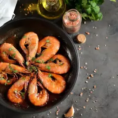 Pyszne krewetki w sosie, część dania frutti di mare, skropione natką pietruszki, gotowe do podania.