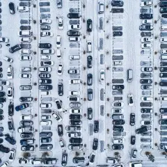 Zimowy parking z wieloma samochodami. Wygląda, jakby druga rata OC po terminie, bo tyle aut stoi w śniegu.