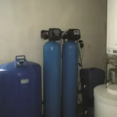 System do uzdatniania wody: niebieski zbiornik, dwa pionowe cylindry z panelami sterowania i biały bojler.