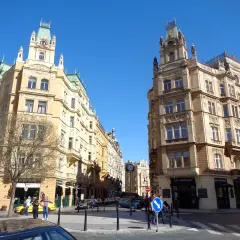 Ulica w praskiej dzielnicy żydowskiej, z secesyjnymi kamienicami i błękitnym niebem.