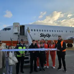 Grupa osób przecina wstęgę przed samolotem SkyUp Airlines. Inauguracja lotów do Szarm El-Szejk. Lotnisko nad morzem.