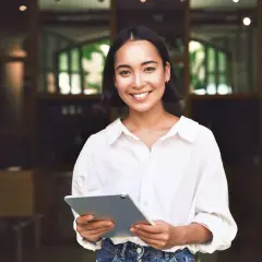 Junge Frau mit Tablet lächelt. Sie plant ihr Eventmanagement Studium dual und ist bereit für neue Herausforderungen.